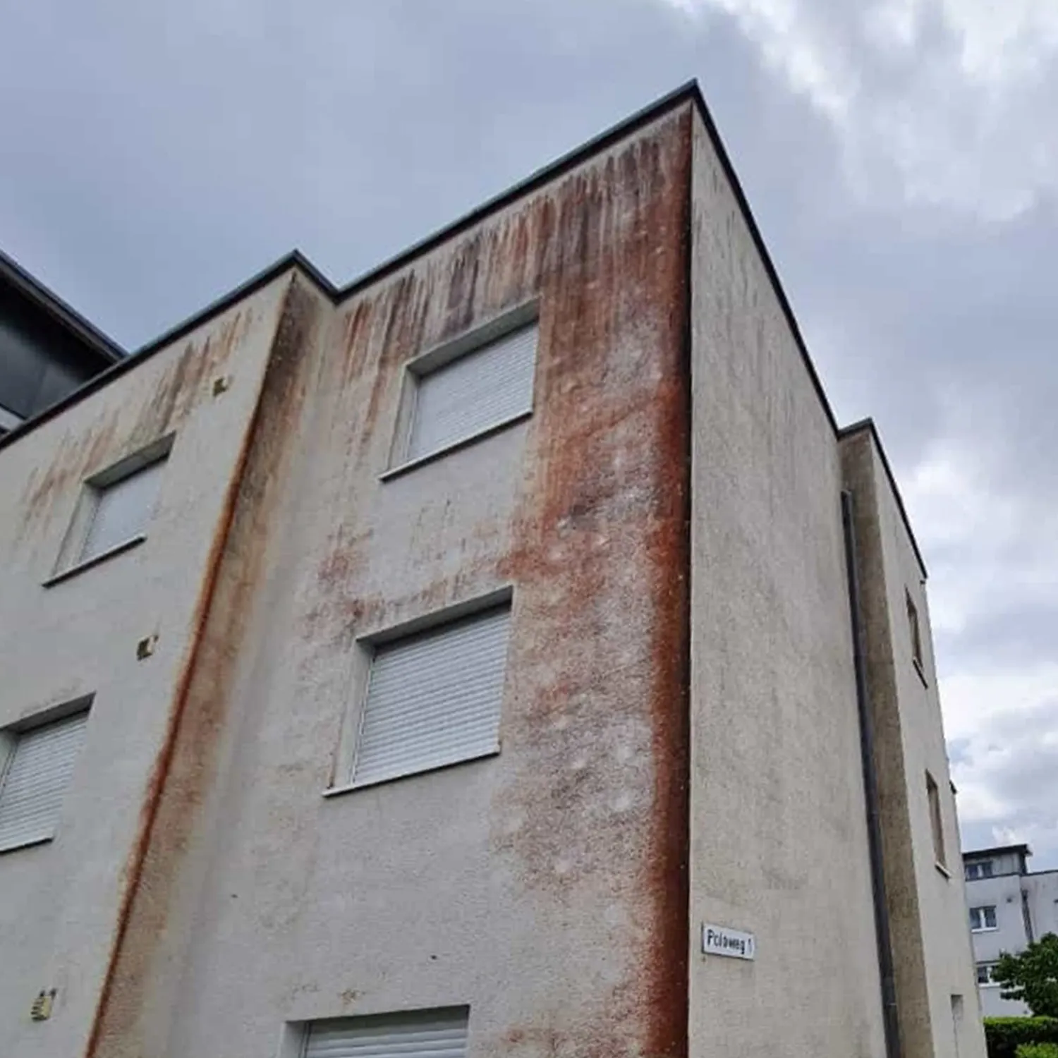 Hausfassade mit starken Rostspuren und Verschmutzungen an der Gebäudeecke – Fassadenreinigung dringend nötig