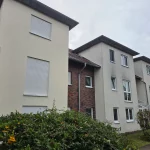 Gereinigte Hausfassade im Vergleich zu benachbarten Gebäuden mit sichtbaren Verschmutzungen